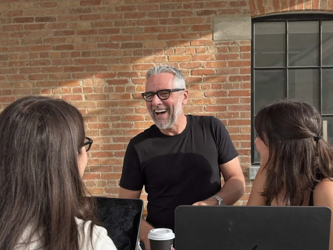 Marc laughing with two people at a table in a brick loft