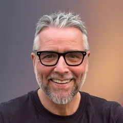 Marc Kleinmann smiling, in black glasses